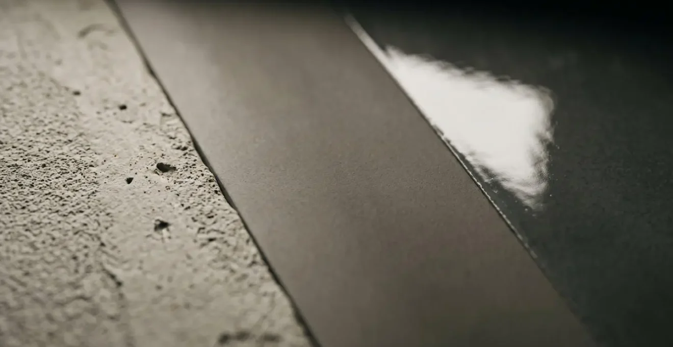 Trois echantillons de murs prepares montrant differents niveaux de finition de peinture sous eclairage rasant